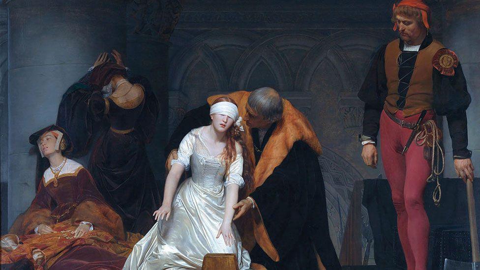 The Execution of Lady Jane Grey in the Tower of London in the Year 1554 by Paul Delaroche. The painting shows Lady Jane in white in the middle reaching for the wooden block, helped by a man in black and orange. On her right are two women attendants in a state of collapse. On her left is the executioner in red and black leaning on his axe.