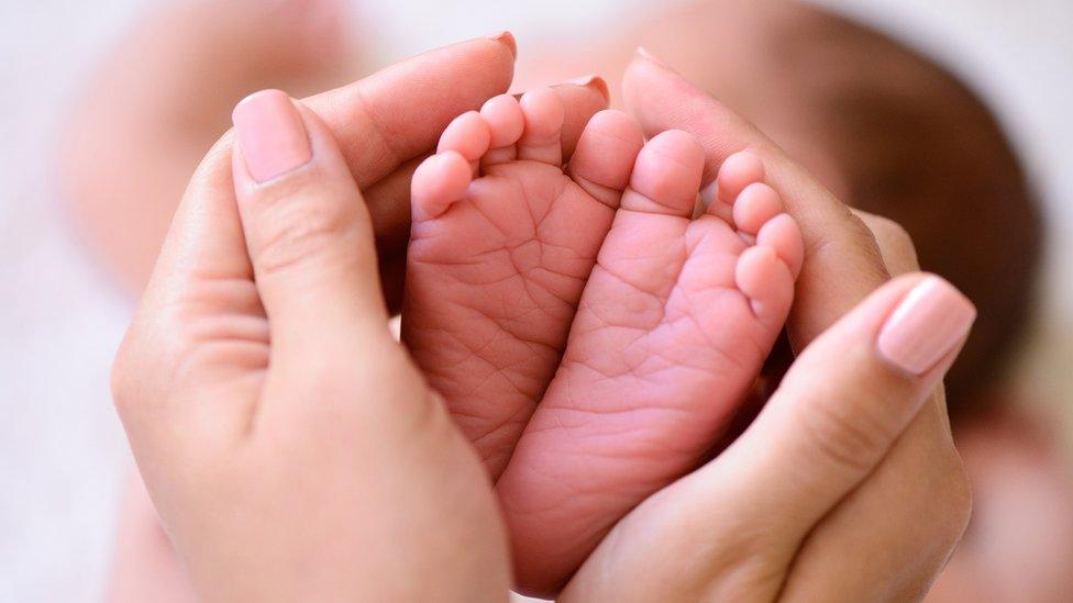 Adult's hands around a baby's feet