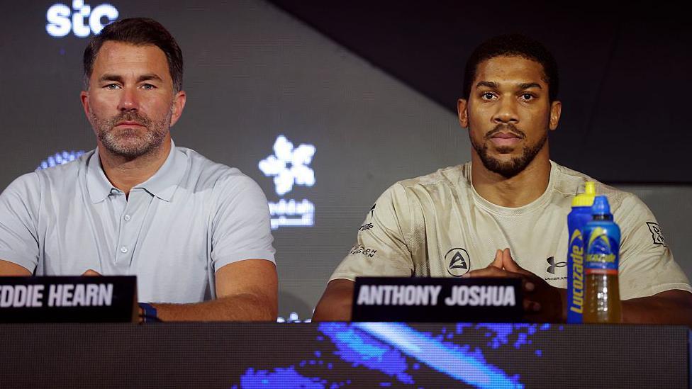 Eddie Hearn and Anthony Joshua sit at a table