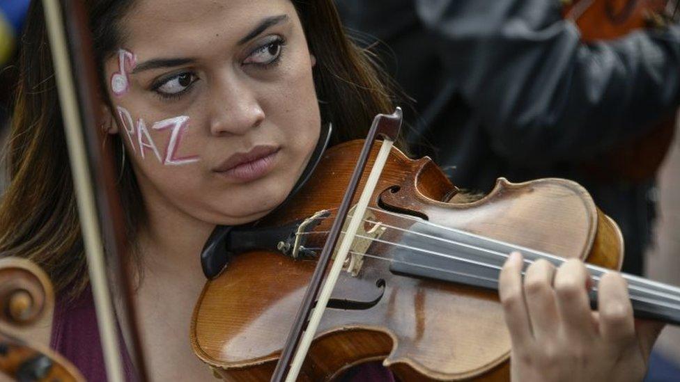 A musician of the conservatory of the National University of Colombia plays the violin with her face painted that reads "peace" during protests and a national strike against the government of President Ivan Duque on November 27, 2019 in Bogota, Colombia