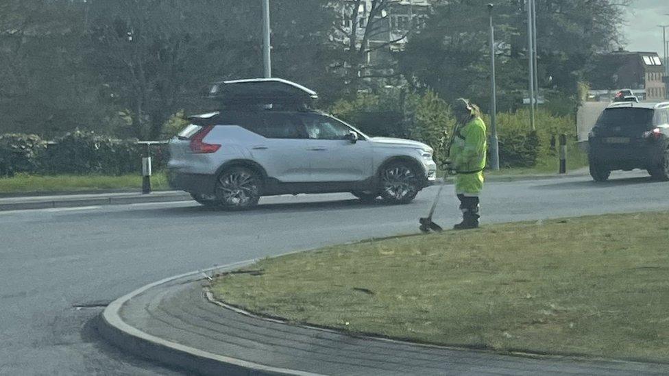 The council worker strimming plastic grass