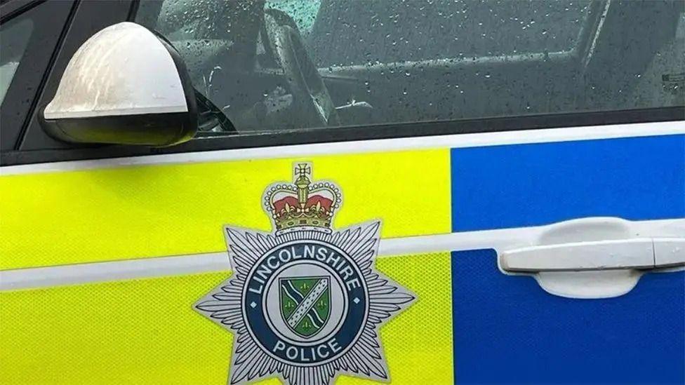 Close-up of a Lincolnshire Police car. The Lincolnshire Police logo is prominent in the picture on the passenger door of the car. 