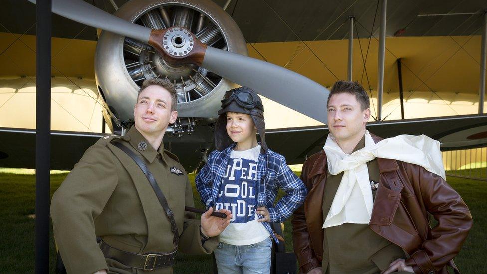 Two serving RAF officers dressed as First World War pilots entertain a youngster.