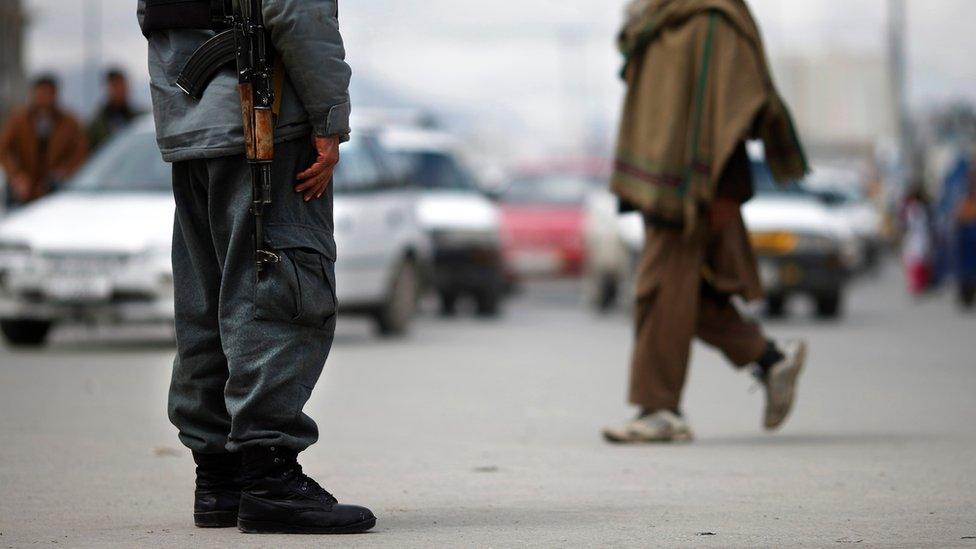 A police officer (L) mans a checkpoint in Kabul - 2014