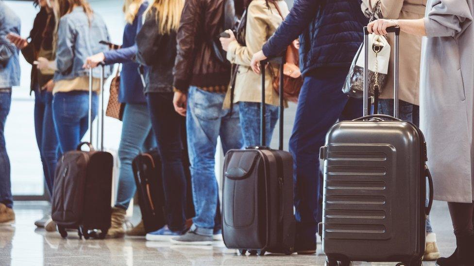 passengers with luggage in a queue