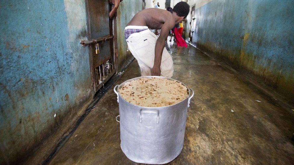 A prisoner pulls a large stock pot filled with rice and beans during lunch inside the National Penitentiary in downtown Port-au-Prince