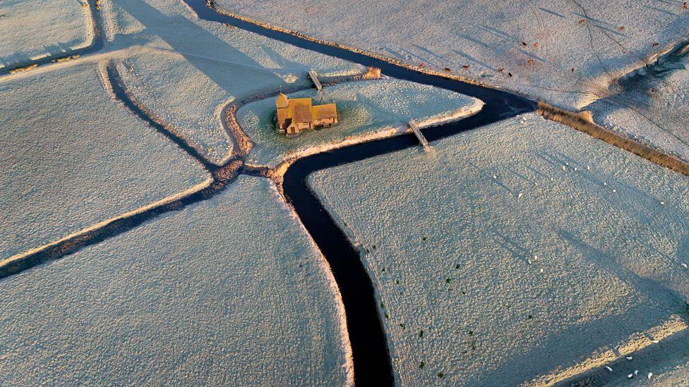 An aerial photo showing St Thomas Becket church surrounded by frosty fields on the Romney Marsh in Kent