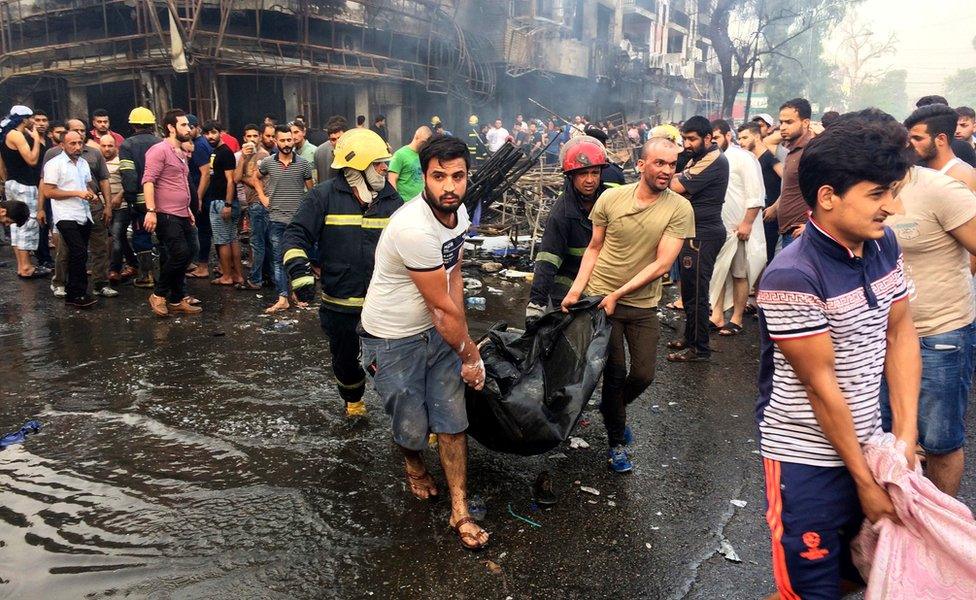 Iraqi firefighters and civilians carry bodies of victims killed in a car bomb at a commercial area in Karrada neighbourhood, Baghdad, Iraq, Sunday, July 3, 2016