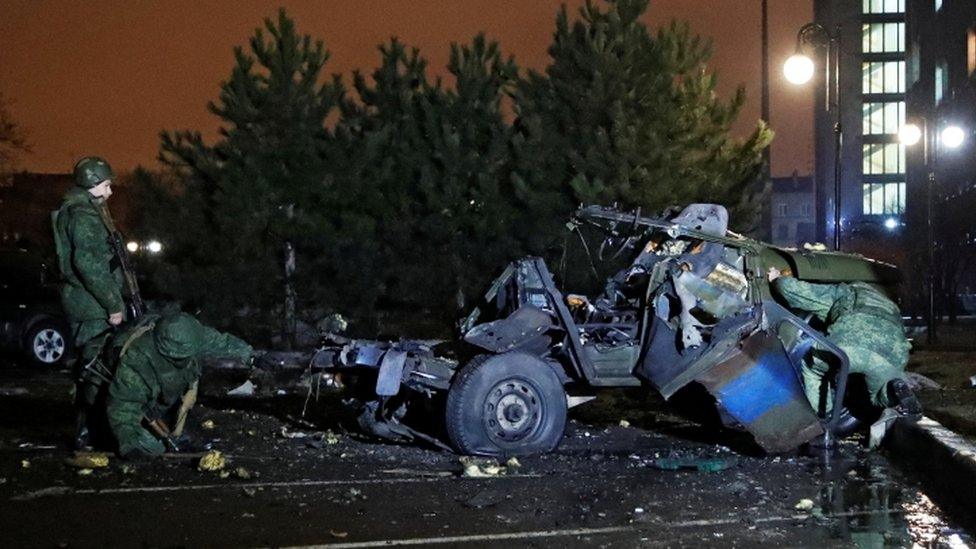 Specialists inspect a wreckage of a car that, according to the local authorities, was blown up near the government building, in the rebel-controlled city of Donetsk, Ukraine February 18, 2022