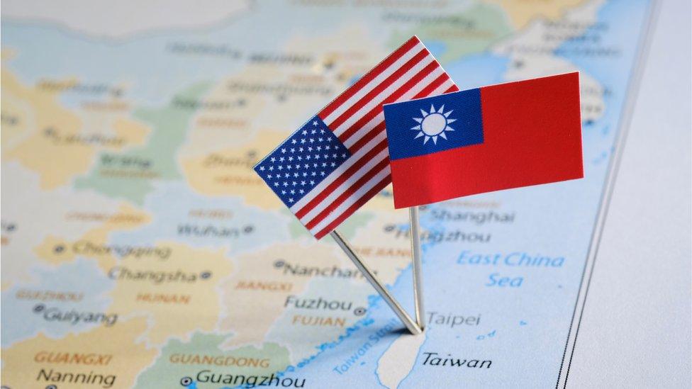 photograph shows taiwan on a world map with a united states flag and a taiwanese flag pinned together in the city of taipei