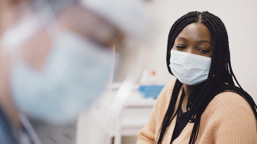 A woman wearing a mask in a medical setting