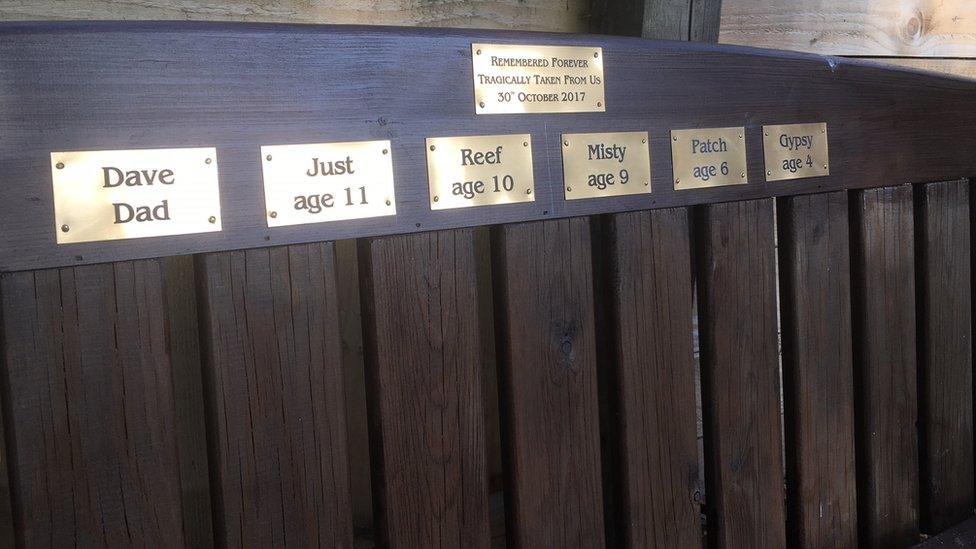 A memorial bench with plaques of the names of the dead