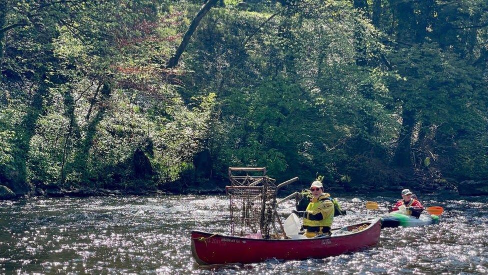 Canoe with rubbish, including shopping trolley,