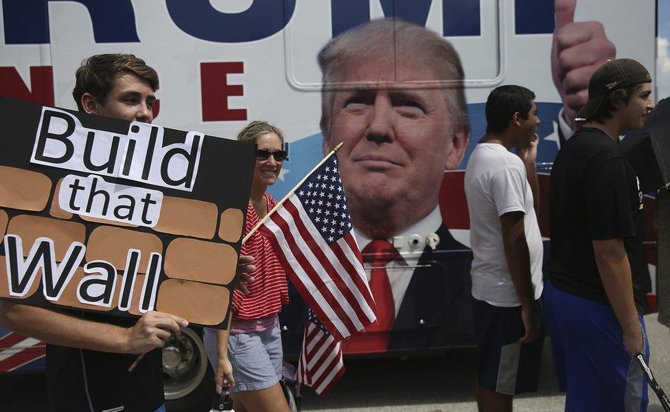 Trump supporters with a sign that says "Build that wall"