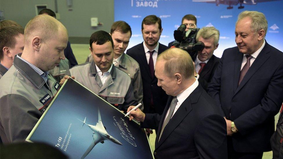 Russian President Vladimir Putin signs a picture of a TU-160M nuclear bomber