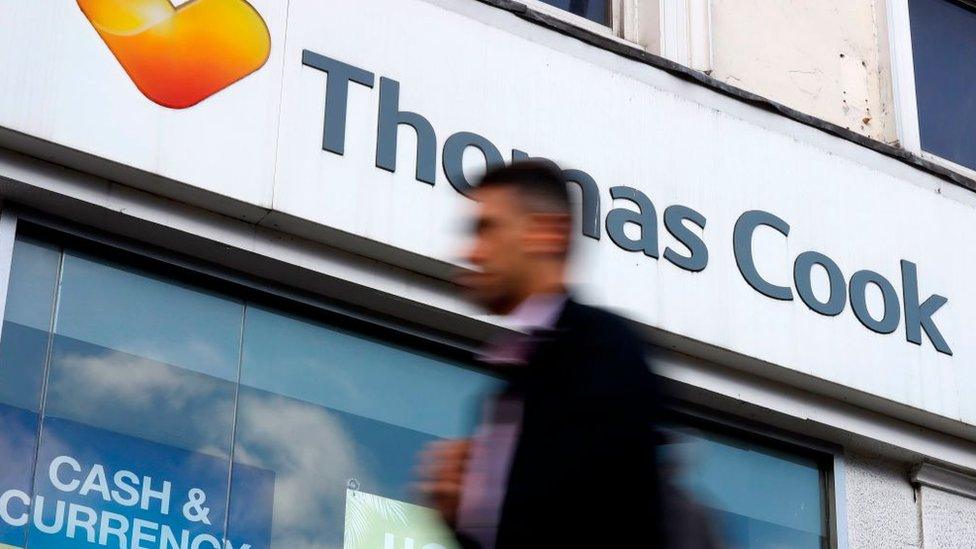 A pedestrian walks past a closed branch of a Thomas Cook travel agent's shop in London