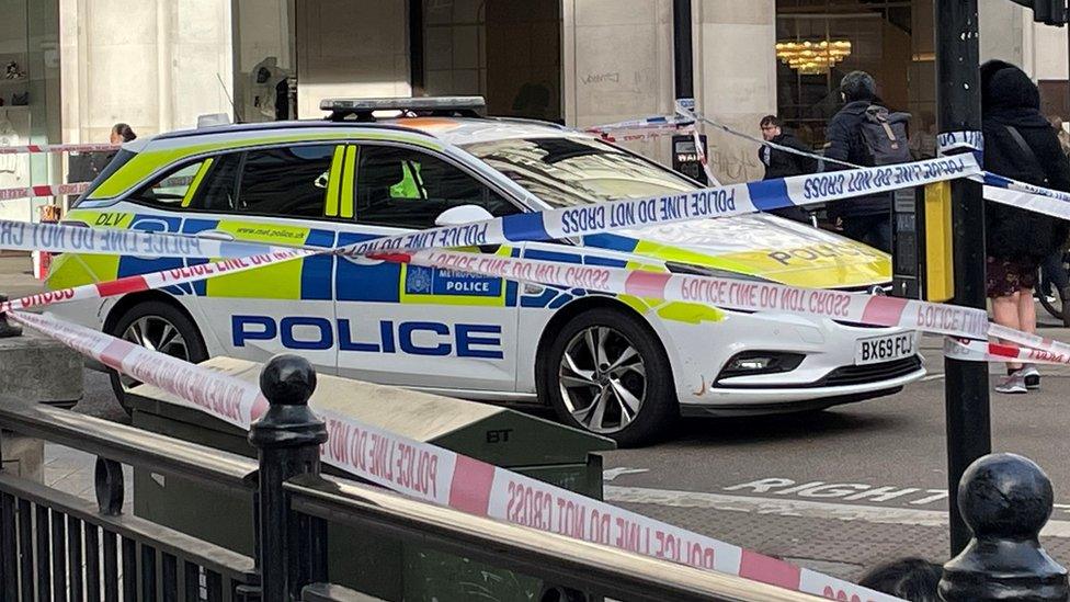 Image of a police car surrounded by multiple cordons by H&M at Oxford Circus.