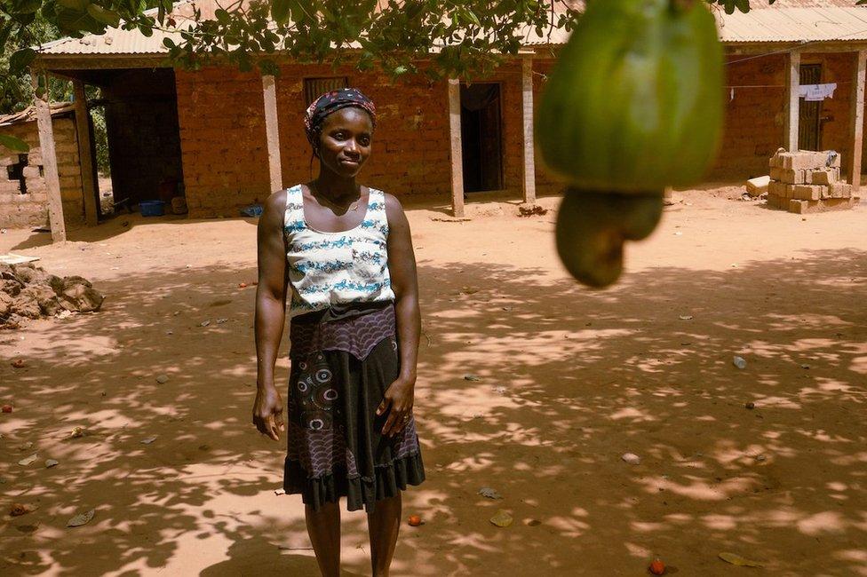 Meia Nianta poses for a portrait outside of her home that sits next to her her 1.5 hectare cashew farm just outside of the capital city, Bissau. She said the harvest starts in March and wraps up around June in the West African country. She usually works from mid-afternoon until late in the evening.