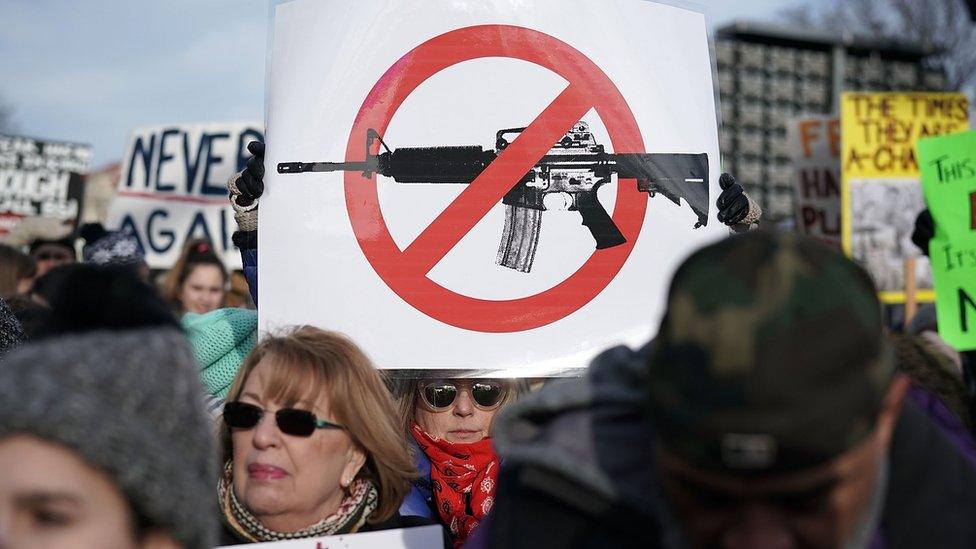 People hold signs as they wait for the beginning of the March for Our Lives rally on 24 March, 2018