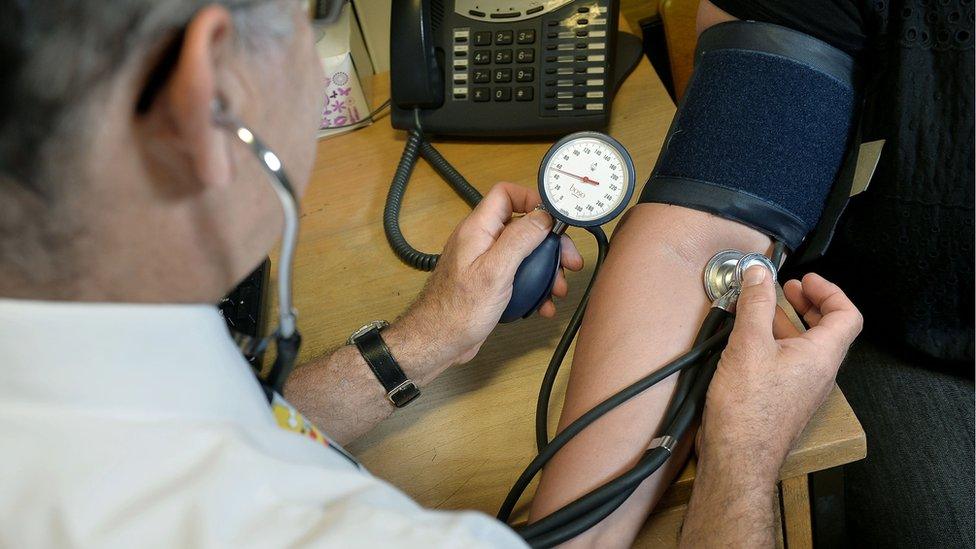 A GP using a stethoscope on a patient