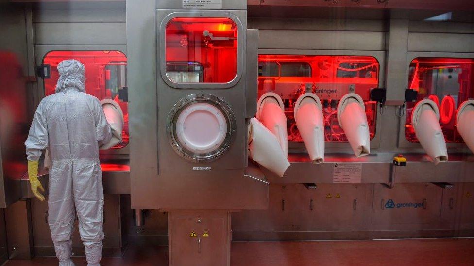 An employee in protective gear works on an assembly line for manufacturing vials of Covishield, AstraZeneca-Oxford's Covid-19 coronavirus vaccine at India's Serum Institute in Pune