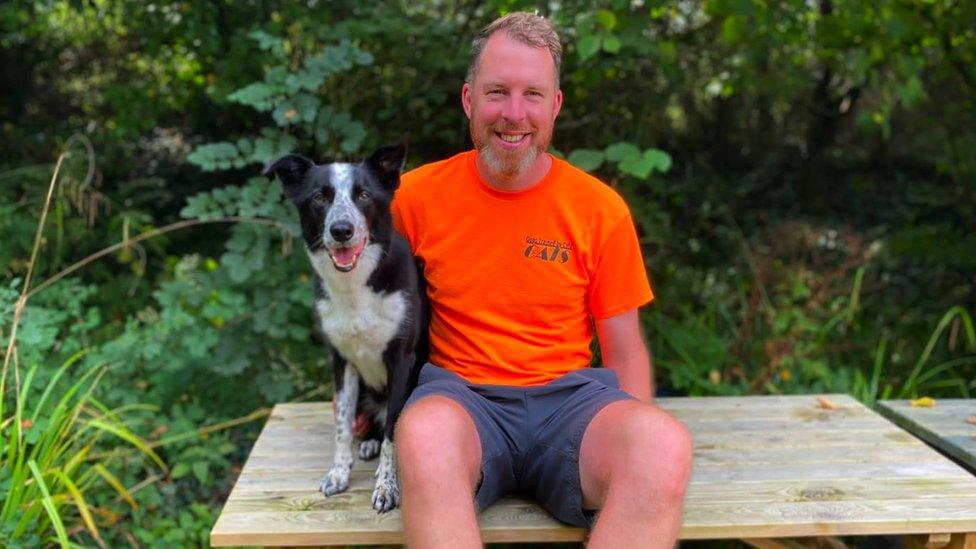 Image of Seb with Buddy the black and white border collie dog sitting on a bench together