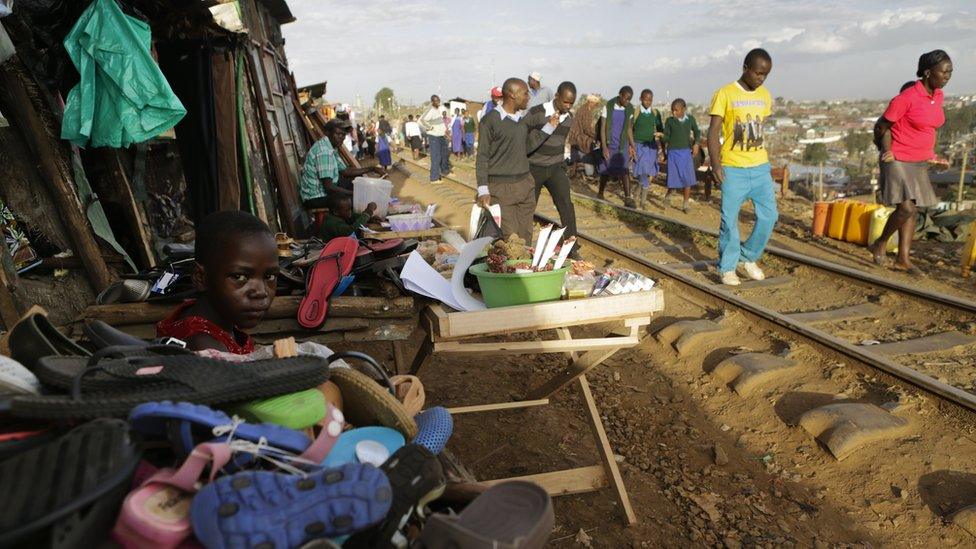 Students walking along a railway track with stall alongside in Kibera, Nairobi, Kenya - Tuesday 7 February 2017