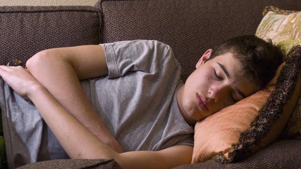 Teenage boy asleep on sofa