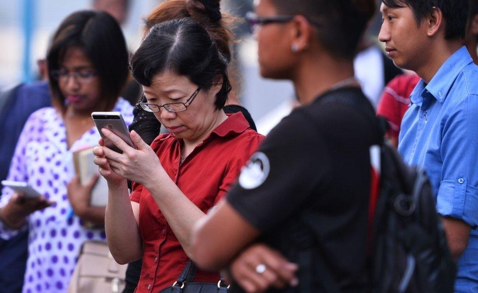 China's consul-general checks her phone at a jetty in Kota Kinabalu after a tourist boat carrying 28 Chinese nationals was reported missing on January 28.