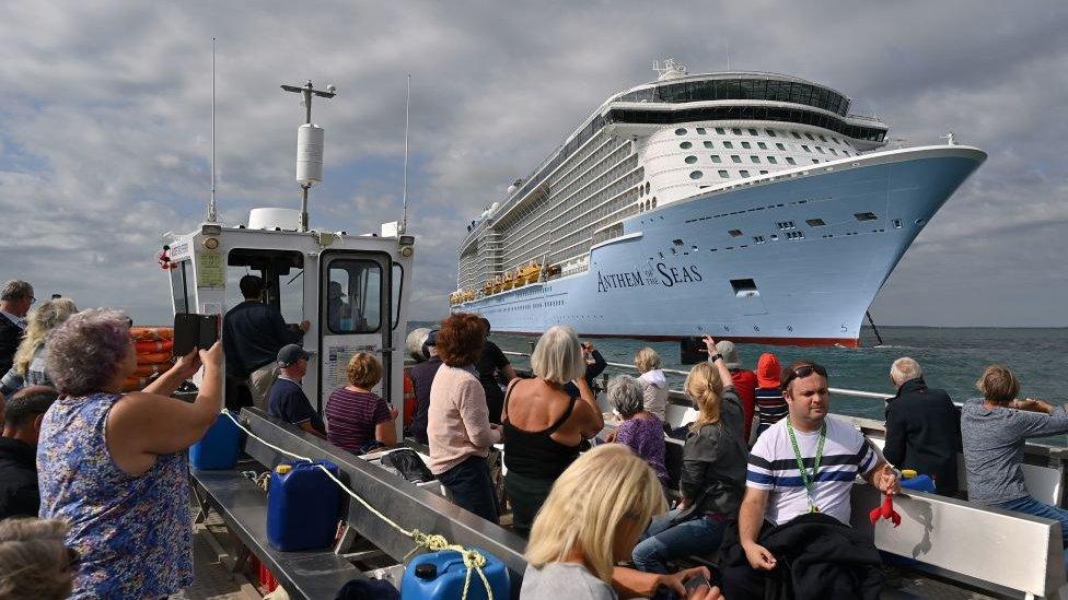 small boat of sight-seekers looking at big cruise ship