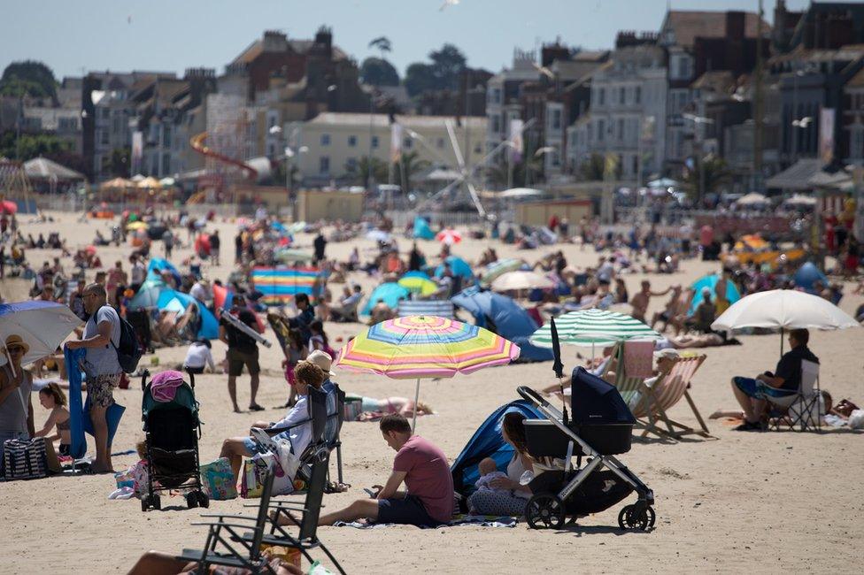 People enjoy the sunny weather at a beach at Weymouth seafront in Dorset, England