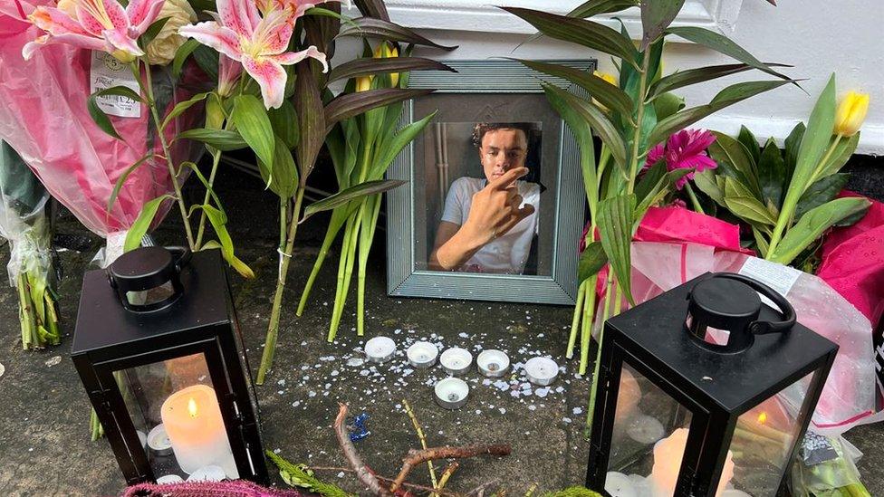 A shrine with flowers and candles and a framed picture of Darrian Williams