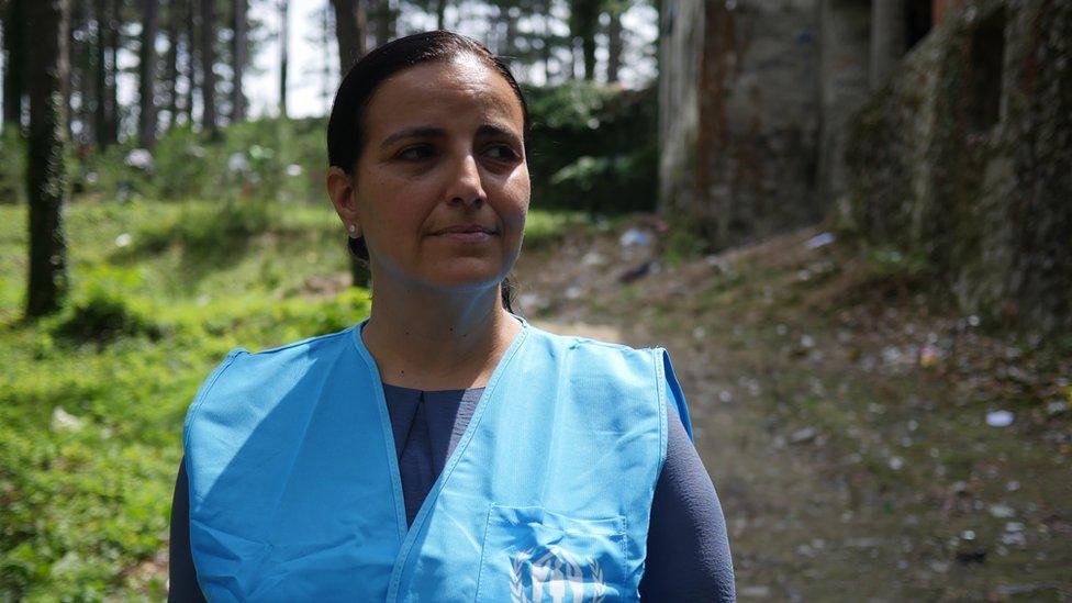 Francesca Bonelli from UNHCR stands near some trees in a green space