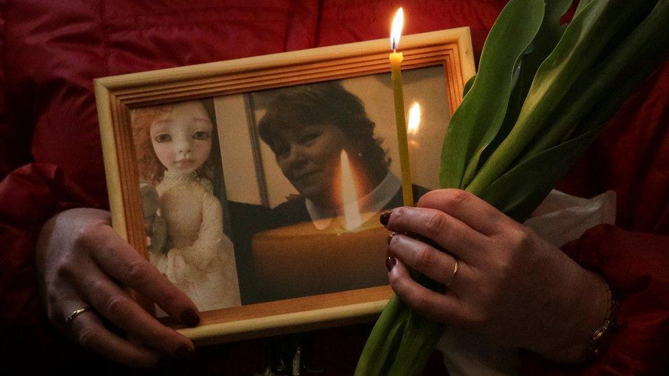 A relative holds a picture of victim of victim Irina Medyantseva at a memorial service in St Petersburg