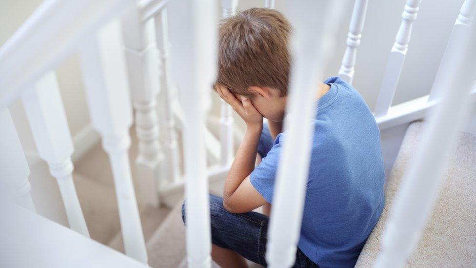 Child sitting on stairs with head in hands