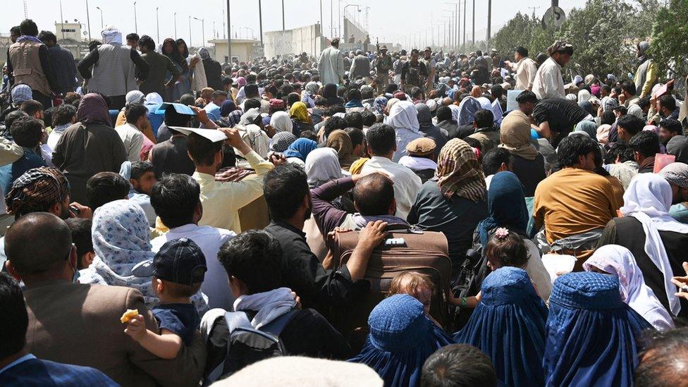 Afghans gather on a roadside near the military part of the airport in Kabul, August 20, 2021