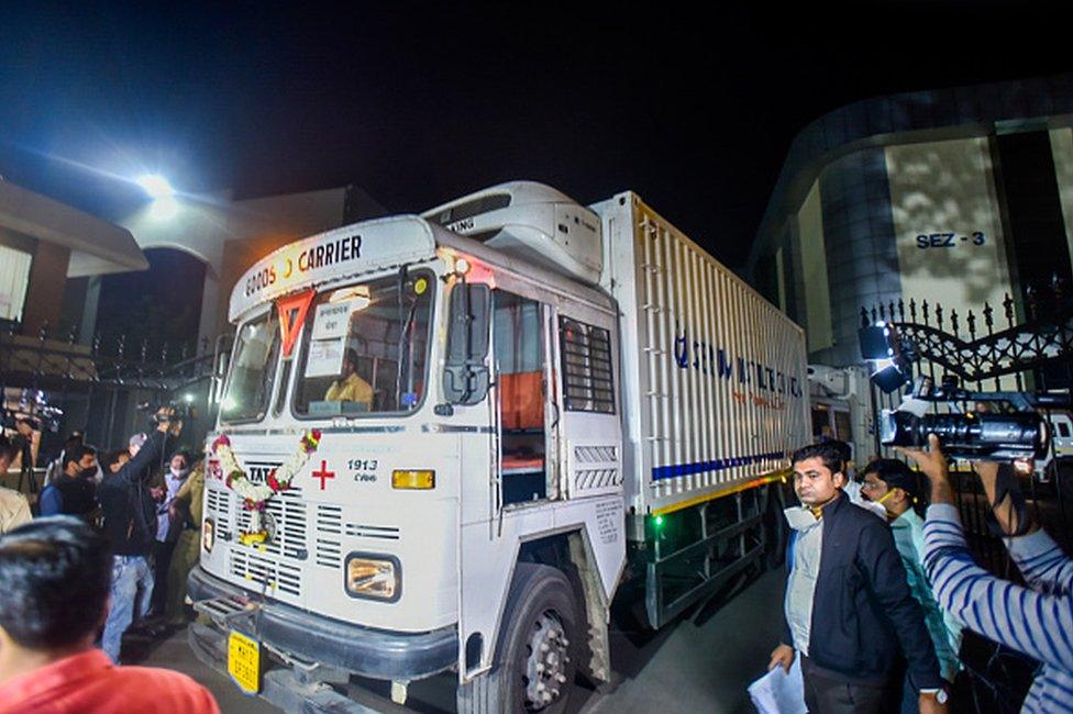 Media personnel surround a refrigerator truck before leaving the Serum Institute of India with vials of Covishield vaccine in Pune early on January 12, 2021.