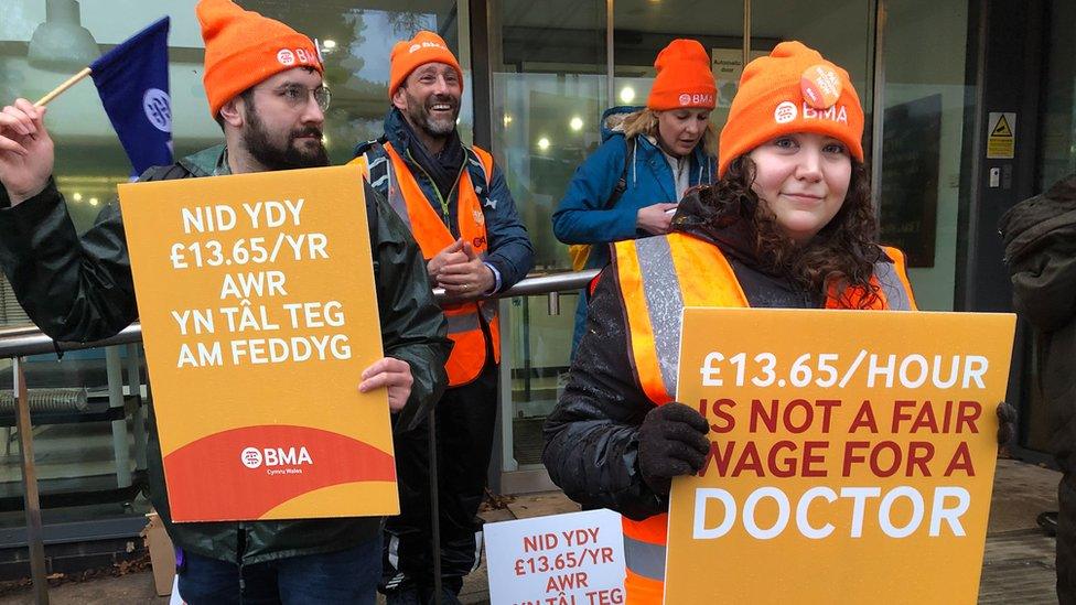 Doctors on strike holding up placards about their pay