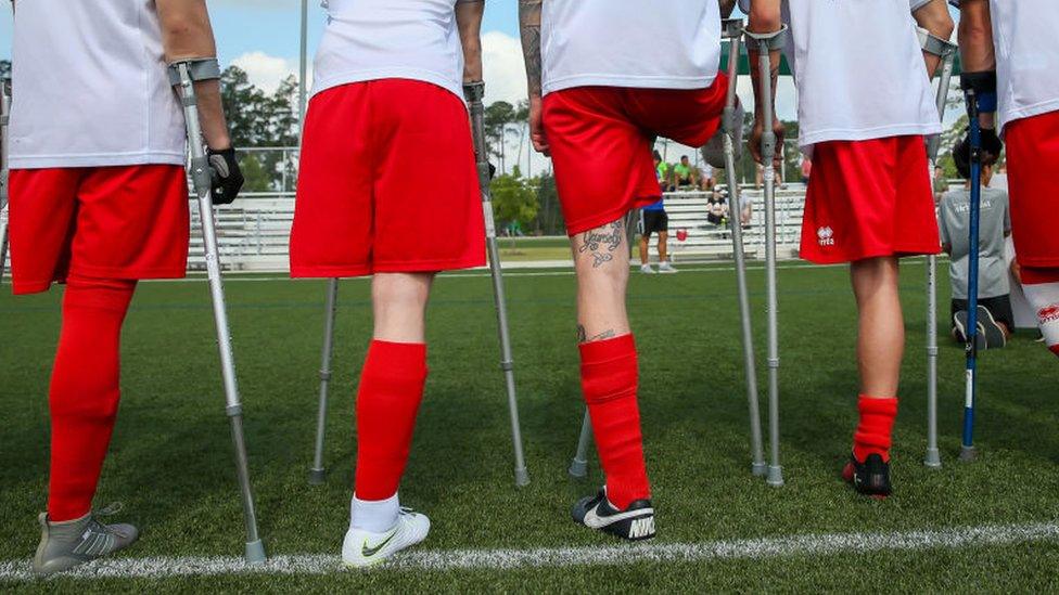 A group of amputee football players stood on a pitch