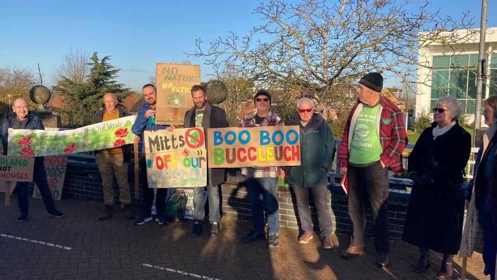 Group of residents outside the council camber with (mainly) cardboard "save the wood" placards