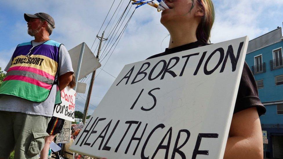 An abortion rights activist holds a placard saying "abortion is healthcare" outside Mississippi's only abortion clinic