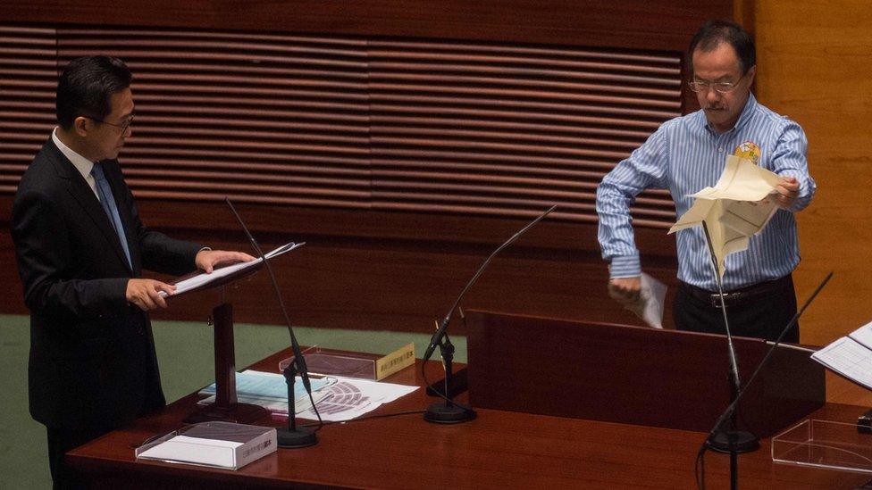 Newly elected lawmaker Fernando Cheung (R) tears a mock "831 ruling" as he stands to take the Legislative Council Oath