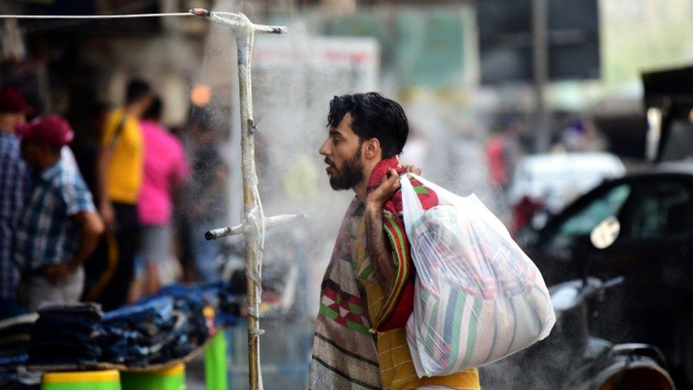 A man stands under a public shower in Baghdad