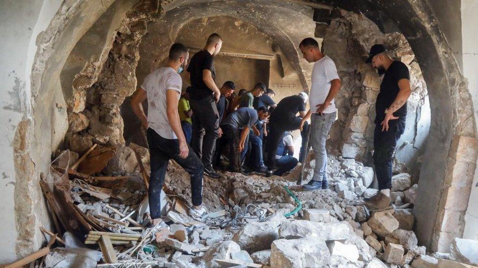 Palestinians inspect a building damaged during clashes between Palestinian militants and Israeli forces in a raid, in Nablus in the Israeli-occupied West Bank August 9, 2022