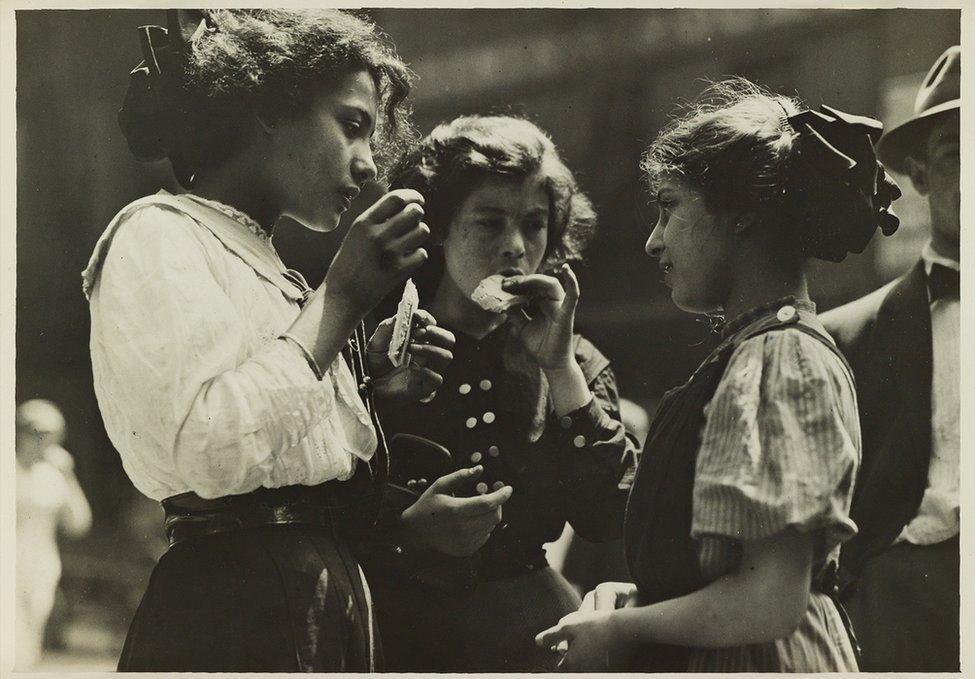 A group of three children eating.