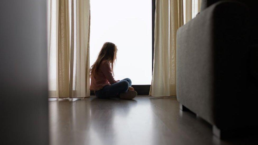 Young girl from behind looking out a window