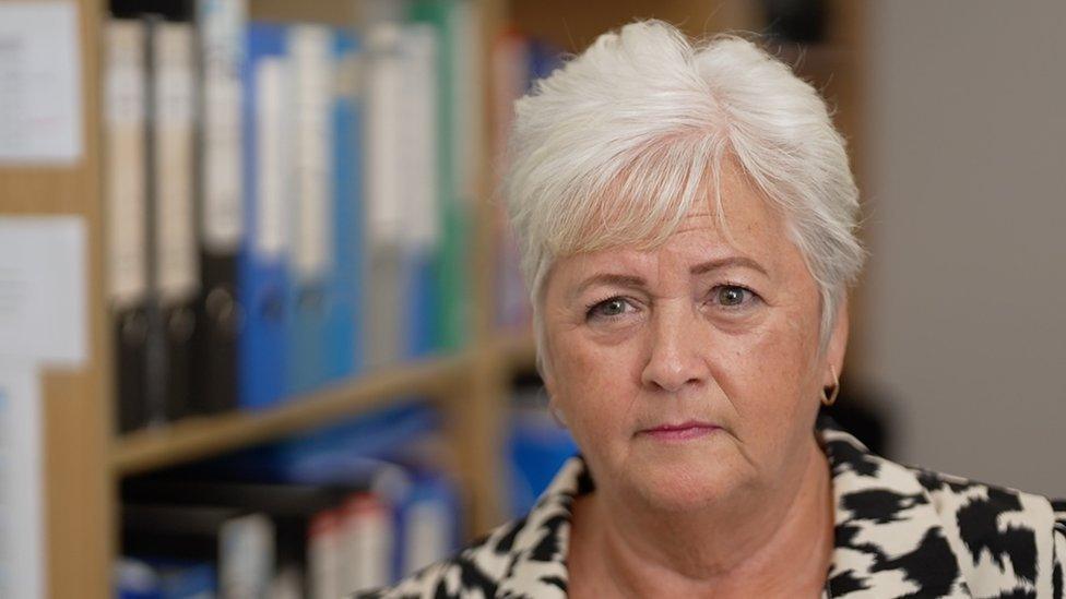 A woman with white hair and a black and white top.