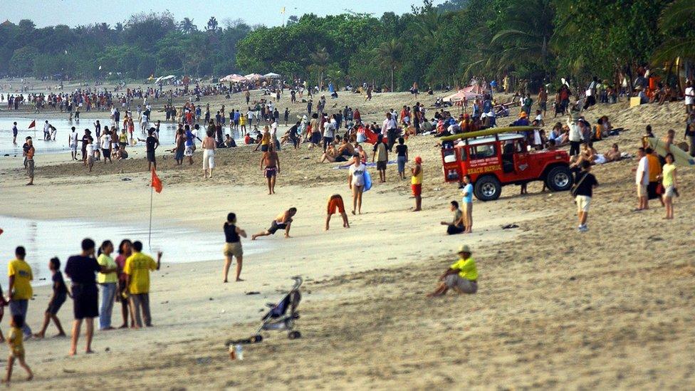 Foreign and local tourists enjoy their evening along a beach in Kuta, on Bali island, 2 October 2005