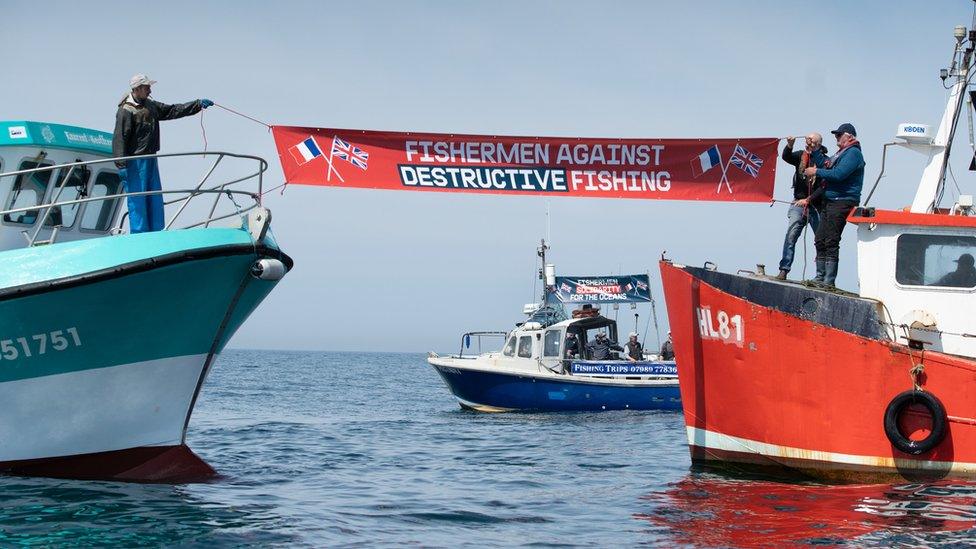 A banner being held between two boats in the Channel