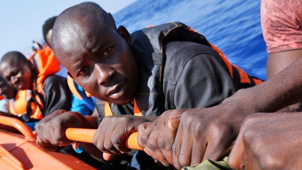 Migrants sit on a Norwegian Coast Guard boat after being transferred from the Italian Navy Ship Fulgosi during a migrant search and rescue mission off the Libyan Coasts, Tuesday, Sept. 1, 2015